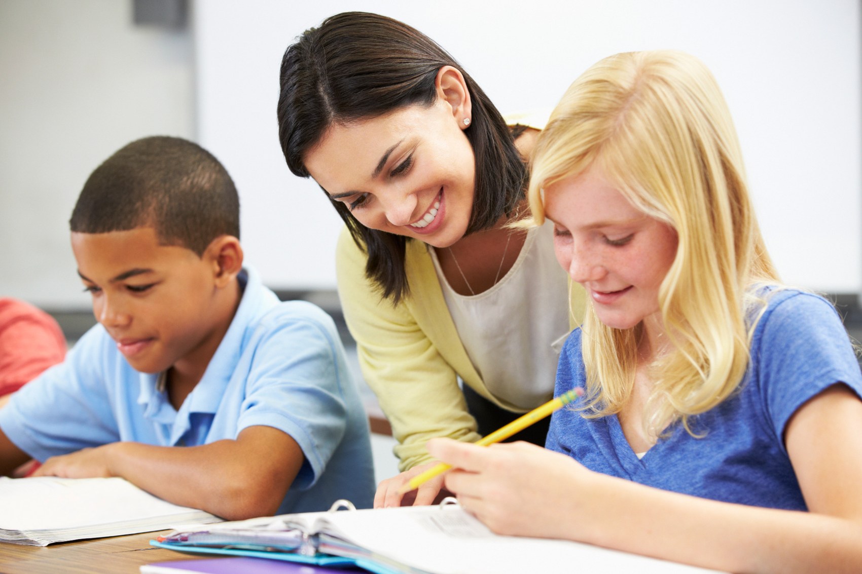 Teacher supporting two children with a learning activity