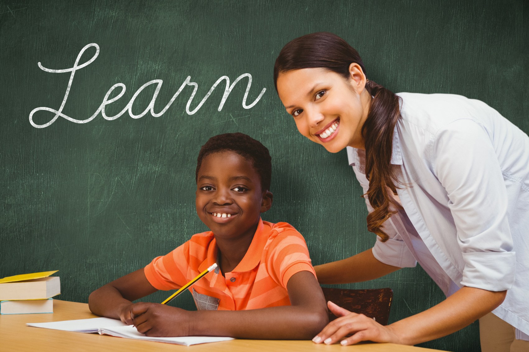 Teacher encouraging a pupil at the classroom chalkboard