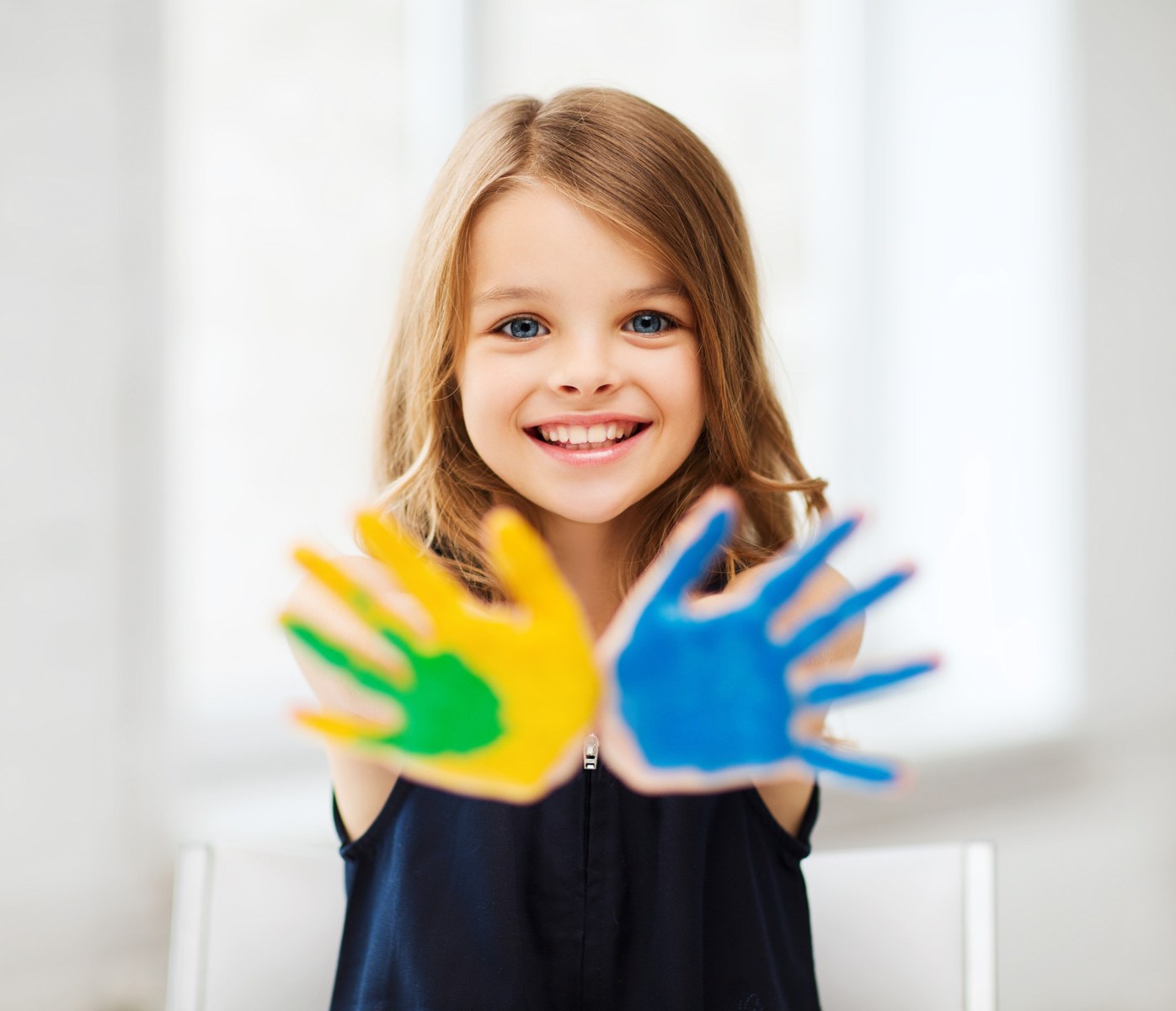 Child holding colourful painted hands forward
